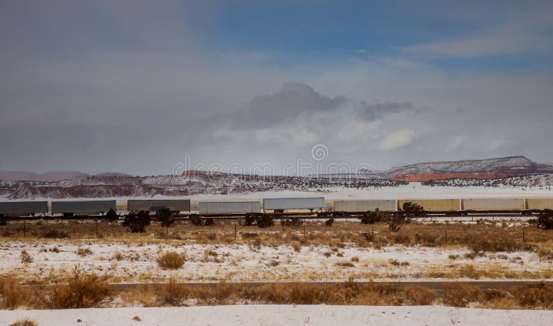 Moving long freight container train along the railroad tracks, transporting and delivering goods across the desert in Arizona