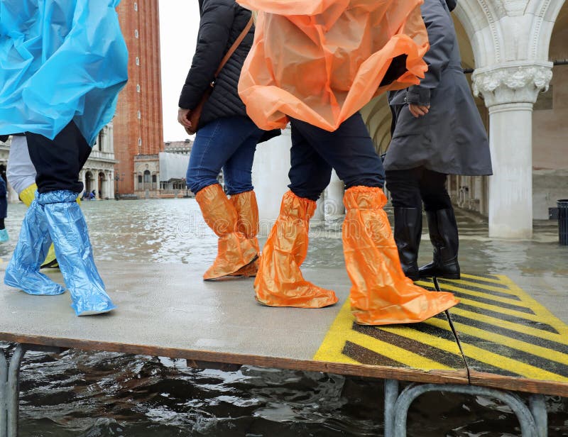 moving people with rain coats and plastic leggings on the footbridge in Venice in Italy during the flood. moving people with rain coats and plastic leggings on the footbridge in Venice in Italy during the flood