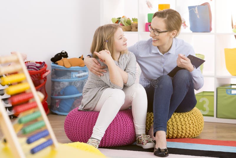 Young speech therapist working with child in colorful educational playroom. Young speech therapist working with child in colorful educational playroom