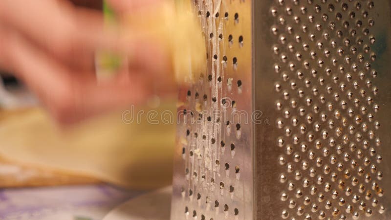 Mozzarella cheese passing through grater shot of a piece of cheese