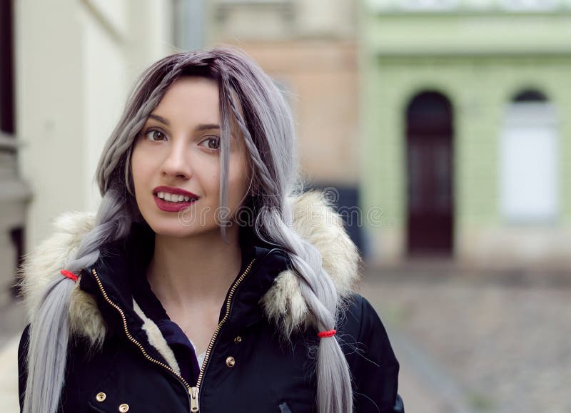 Moça bonita com cabelo da trança do cinza de prata, bordos vermelhos que vestem para baixo o revestimento preto andando na rua no foto de stock royalty free Moça bonita com cabelo da trança do cinza de prata, bordos vermelhos que vestem para baixo o revestimento preto andando na rua no foto de stock royalty free