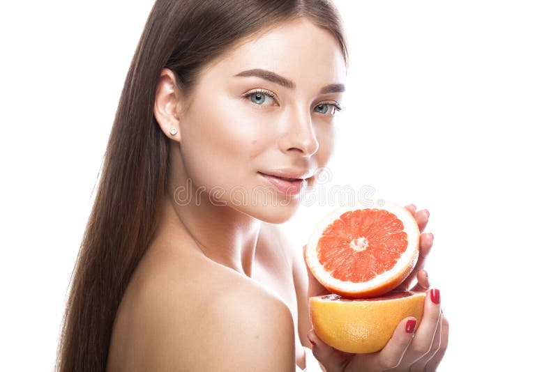 Moça bonita com uma composição natural clara e pele perfeita com a toranja em sua mão Face da beleza imagem de stock Moça bonita com uma composição natural clara e pele perfeita com a toranja em sua mão Face da beleza imagem de stock