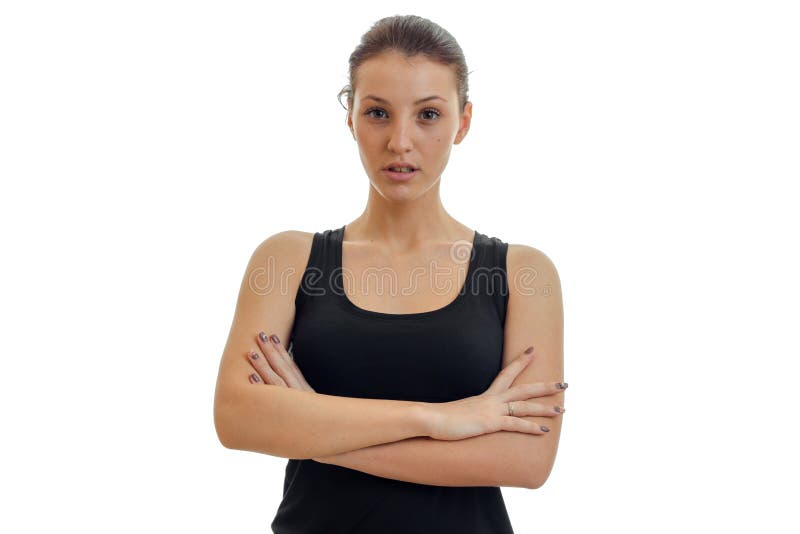 Beautiful young girl in the black shirt looks into the camera, arms folded on chest close-up isolated on white background. Beautiful young girl in the black shirt looks into the camera, arms folded on chest close-up isolated on white background