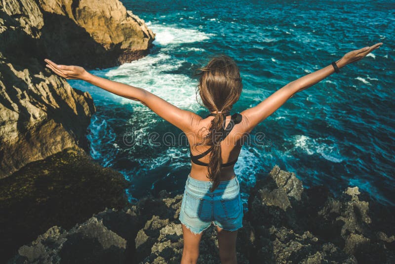 Moça com os braços aumentados acima Ilha de Nusa Penida imagens de stock Moça com os braços aumentados acima Ilha de Nusa Penida imagens de stock