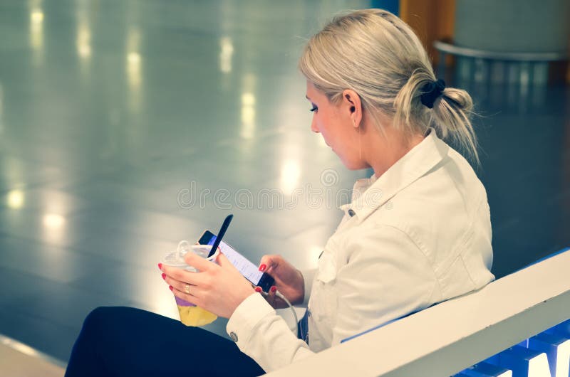 Moça com um vidro do plástico enchido com o suco, sentando-se em um terminal de aeroporto fotografia de stock Moça com um vidro do plástico enchido com o suco, sentando-se em um terminal de aeroporto fotografia de stock