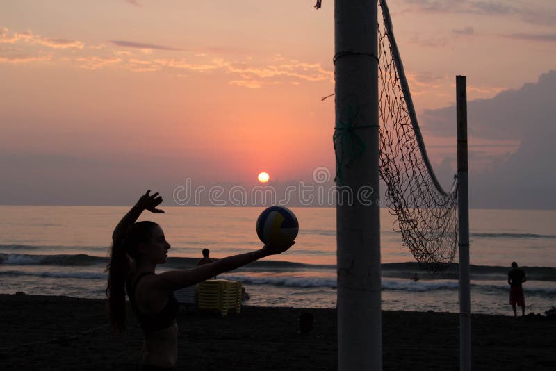 Moça na praia, guardando a bola nas mãos Redes do voleibol na praia imagem de stock royalty free Moça na praia, guardando a bola nas mãos Redes do voleibol na praia imagem de stock royalty free