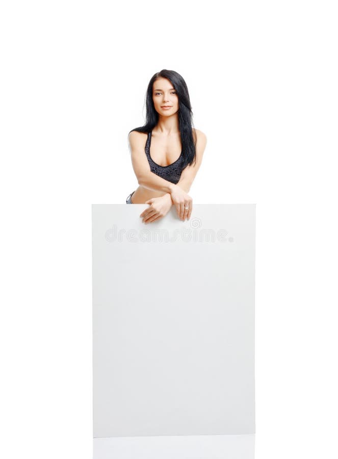 Moça 'sexy' que está e que mantém uma placa branca isolada em w fotografia de stock Moça 'sexy' que está e que mantém uma placa branca isolada em w fotografia de stock
