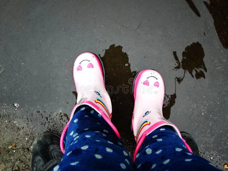 Moças com as botas cor-de-rosa com seu pai que tem a parte externa do divertimento na rua após a chuva fotografia de stock Moças com as botas cor-de-rosa com seu pai que tem a parte externa do divertimento na rua após a chuva fotografia de stock