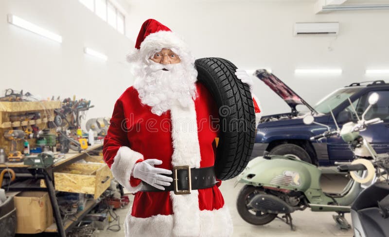 Moș Crăciun într-un garaj auto care transportă o anvelopă de mașină royalty free stock image