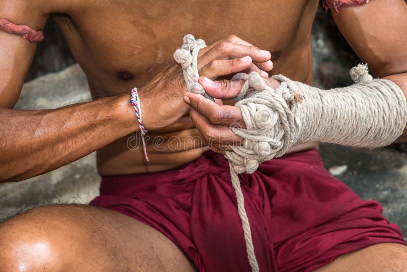 Muay thai o thai boxeador que pone vendas al viejo estilo en las manos preparándose para luchar foto de archivo