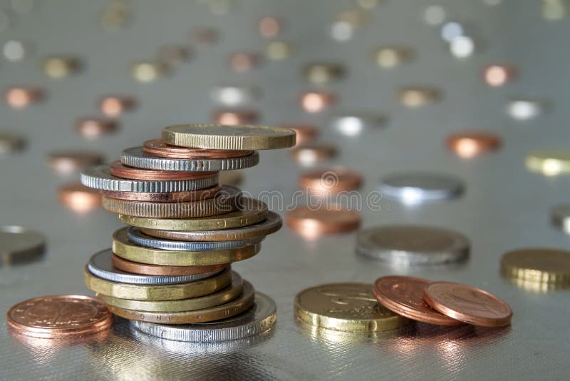 Mucchio delle dimensioni differenti e dei colori delle monete brillanti impilato irregolarmente su a vicenda su fondo astratto bl fotografia stock libera da diritti Mucchio delle dimensioni differenti e dei colori delle monete brillanti impilato irregolarmente su a vicenda su fondo astratto bl fotografia stock libera da diritti