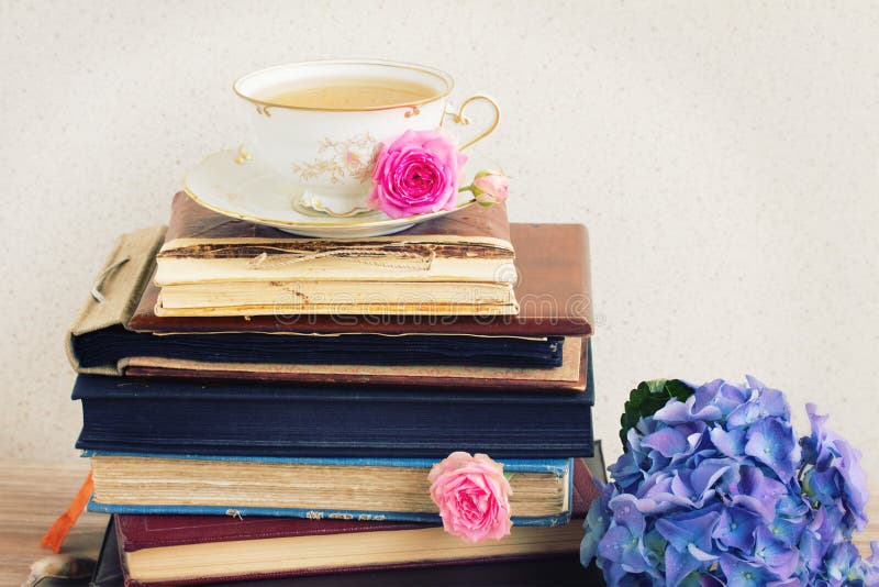 Pile of vintage books and mail with antique cup of tea and flowers. Pile of vintage books and mail with antique cup of tea and flowers