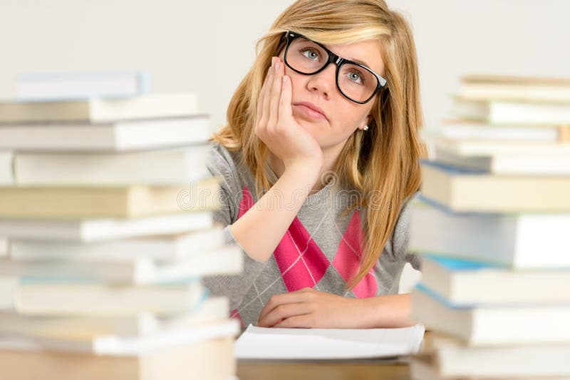 Muchacha aburrida del estudiante entre la pila de libros fotografía de archivo libre de regalías