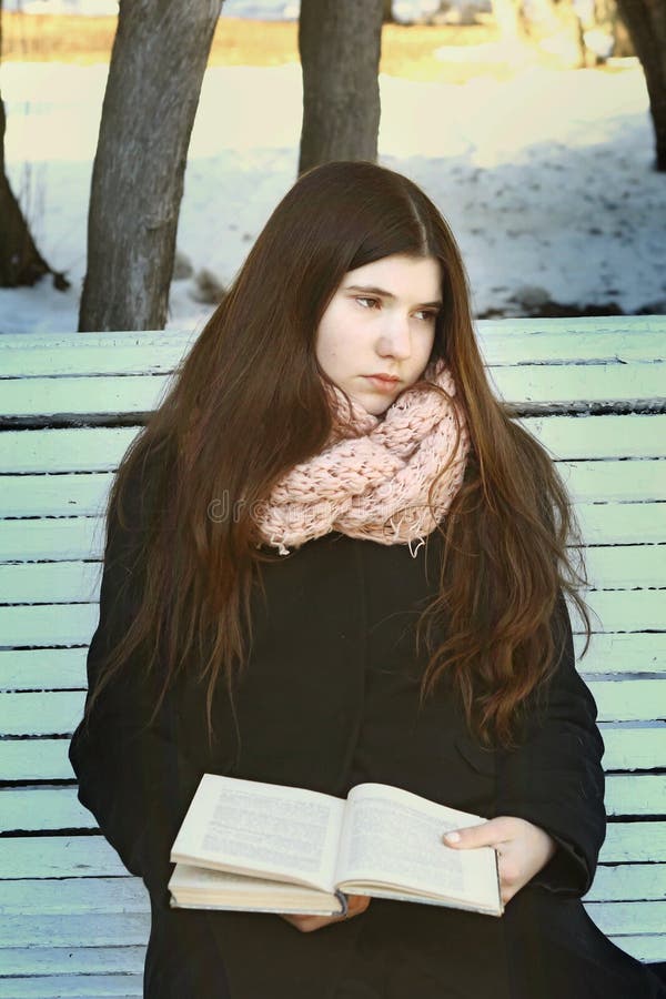 Muchacha adolescente con el pelo oscuro largo con el libro triste foto de archivo libre de regalías Muchacha adolescente con el pelo oscuro largo con el libro triste foto de archivo libre de regalías