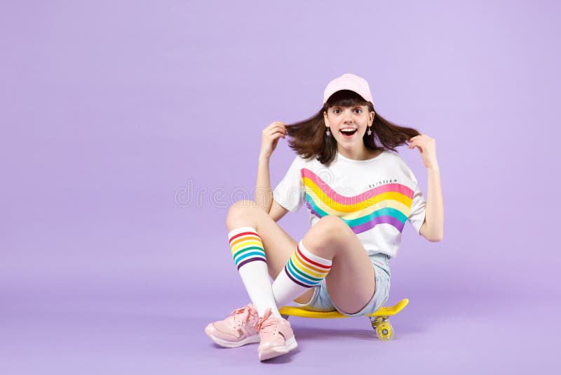Muchacha adolescente emocionada en la ropa viva que se sienta en el monopat?n amarillo, manteniendo abierto de la boca aislado en foto de archivo Muchacha adolescente emocionada en la ropa viva que se sienta en el monopat?n amarillo, manteniendo abierto de la boca aislado en foto de archivo