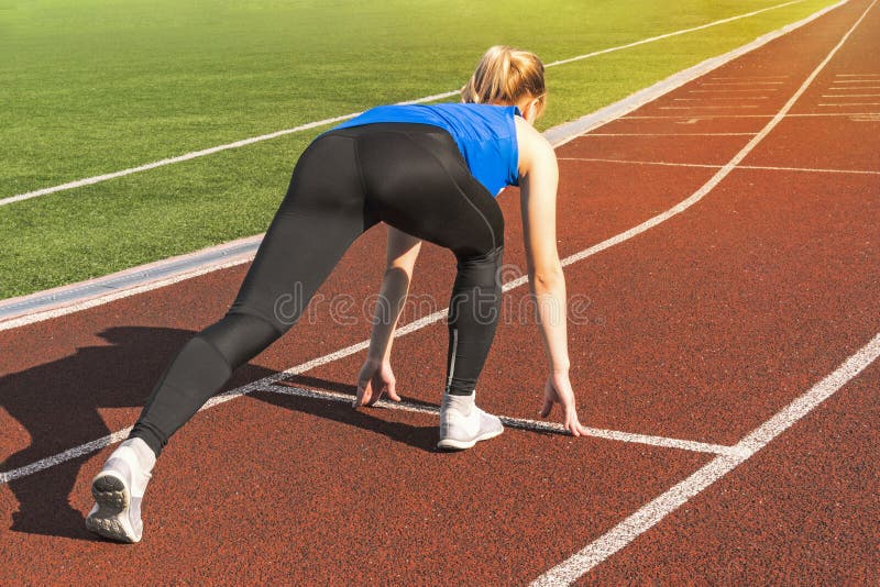 Muchacha adolescente en los bloques el comenzar en una reunión de pista Comienzo de los deportes muchacha en actitud en la línea foto de archivo Muchacha adolescente en los bloques el comenzar en una reunión de pista Comienzo de los deportes muchacha en actitud en la línea foto de archivo