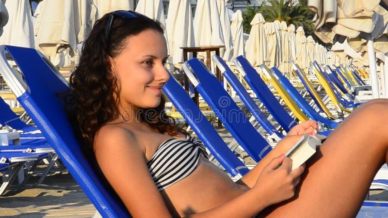 Muchacha adolescente hermosa que lee un libro en la playa