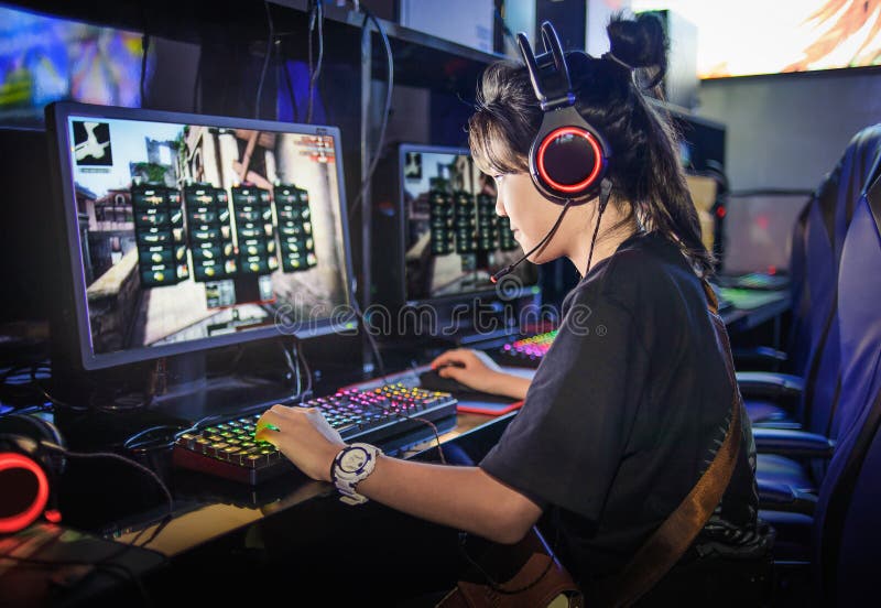 Muchacha adolescente joven que juega a los juegos de ordenador en café de Internet