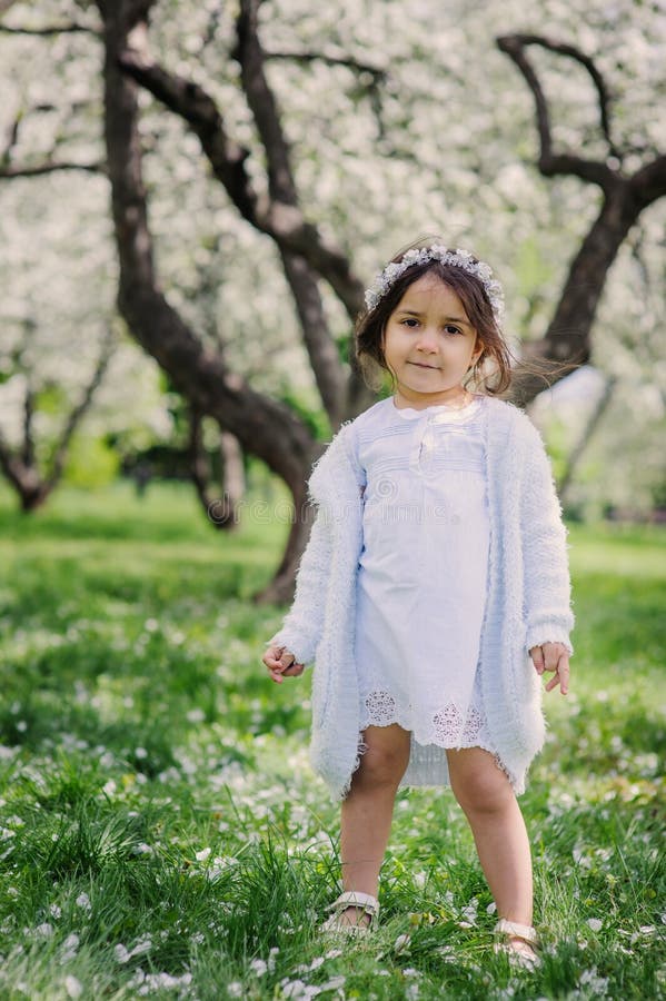 Muchacha adorable del niño del niño en equipo elegante azul claro que camina y que juega en jardín floreciente de la primavera foto de archivo libre de regalías Muchacha adorable del niño del niño en equipo elegante azul claro que camina y que juega en jardín floreciente de la primavera foto de archivo libre de regalías