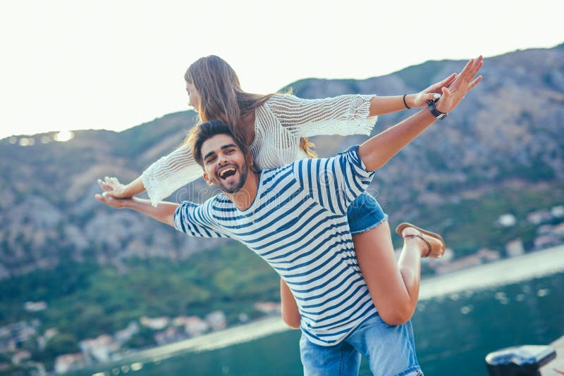 Muchacha alegre que lleva a cuestas en novio joven foto de archivo Muchacha alegre que lleva a cuestas en novio joven foto de archivo