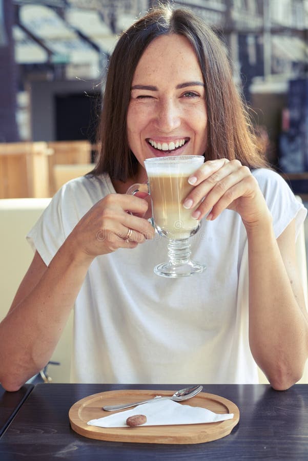 Muchacha alegre que se sienta en un café fotos de archivo libres de regalías Muchacha alegre que se sienta en un café fotos de archivo libres de regalías