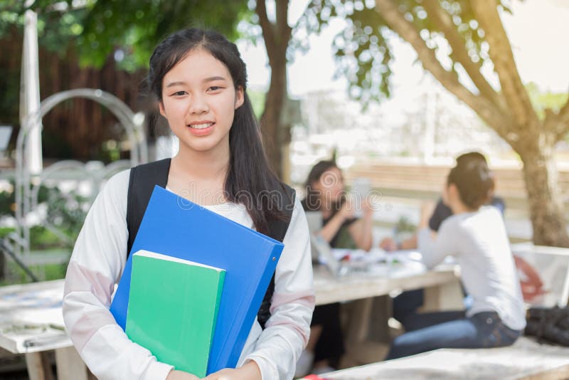 Muchacha asiática del estudiante que sostiene el libro en campus y escuela imagen de archivo Muchacha asiática del estudiante que sostiene el libro en campus y escuela imagen de archivo