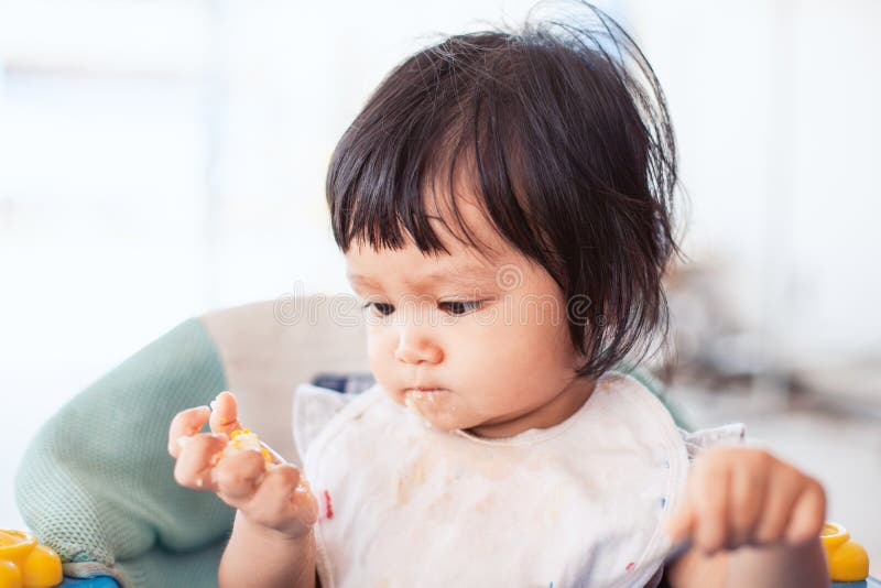 Muchacha asiática del niño del bebé lindo que come la comida sana sola imagenes de archivo Muchacha asiática del niño del bebé lindo que come la comida sana sola imagenes de archivo
