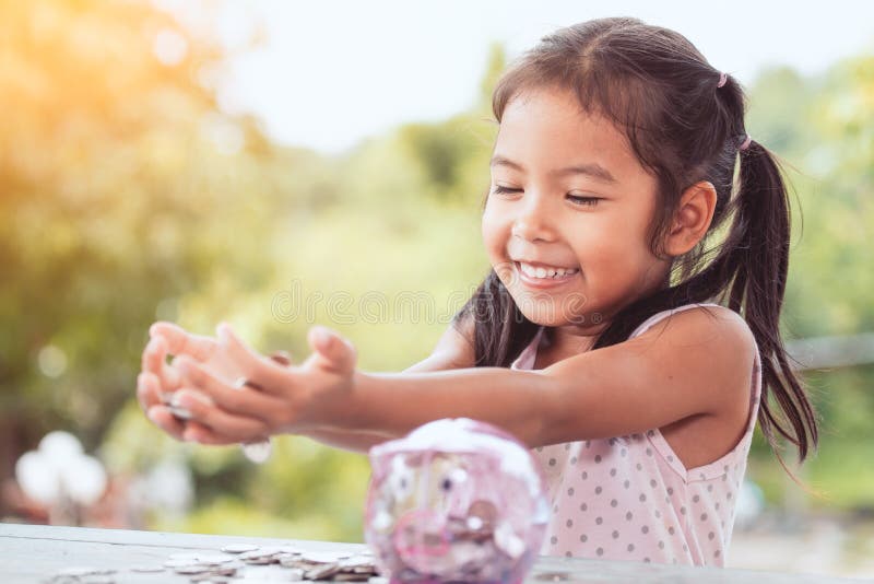 Muchacha asiática feliz del pequeño niño que le muestra el dinero fotos de archivo Muchacha asiática feliz del pequeño niño que le muestra el dinero fotos de archivo