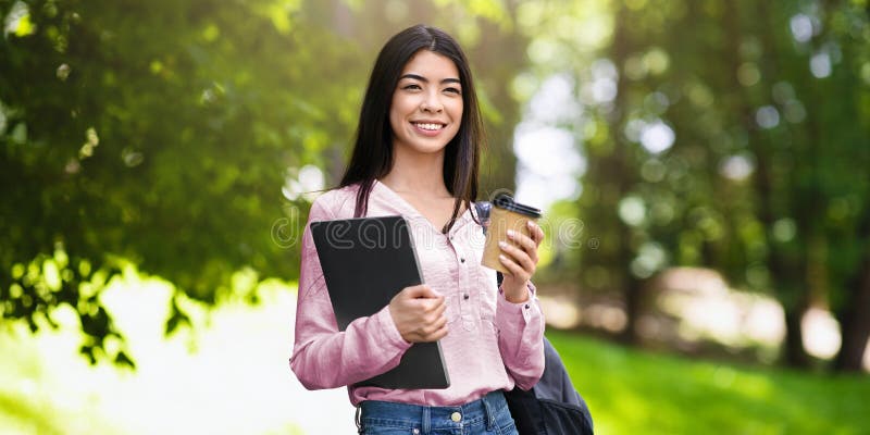 Muchacha Asiática Que Camina Al Aire Libre Con Laptop Y Café En Manos imagen de archivo