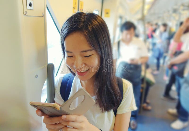 Muchacha asiática que usa un smartphone en tránsito rápido total entre gente imagenes de archivo Muchacha asiática que usa un smartphone en tránsito rápido total entre gente imagenes de archivo