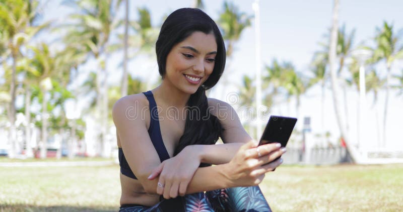 Muchacha bonita con el teléfono en entrenamiento en parque