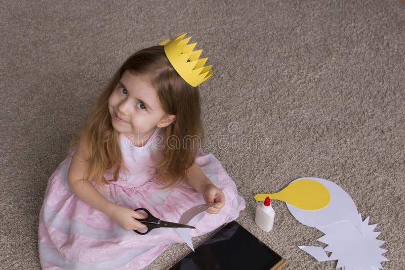 Muchacha bonita con un papel de las tijeras de la corona niña linda que juega con el arte y los materiales para la costura handma imagen de archivo