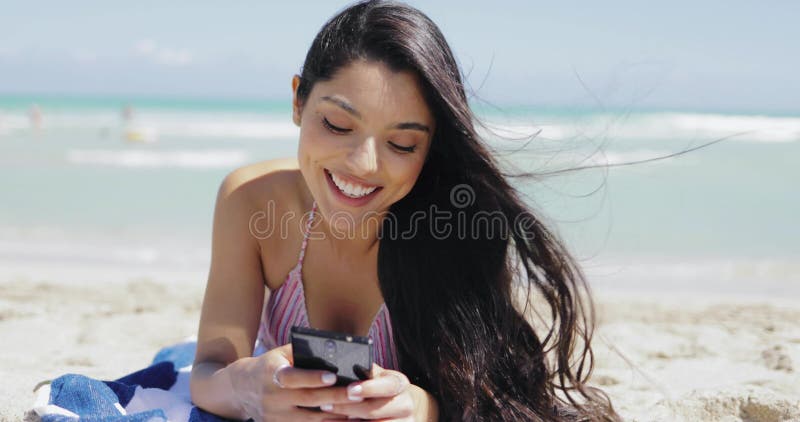 Muchacha bonita que usa el teléfono en la playa