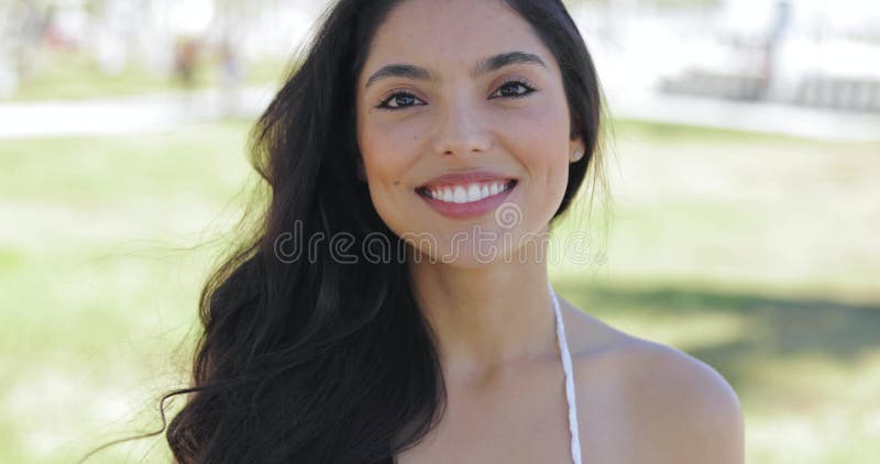 Muchacha brillante contenta que toca el pelo en sol