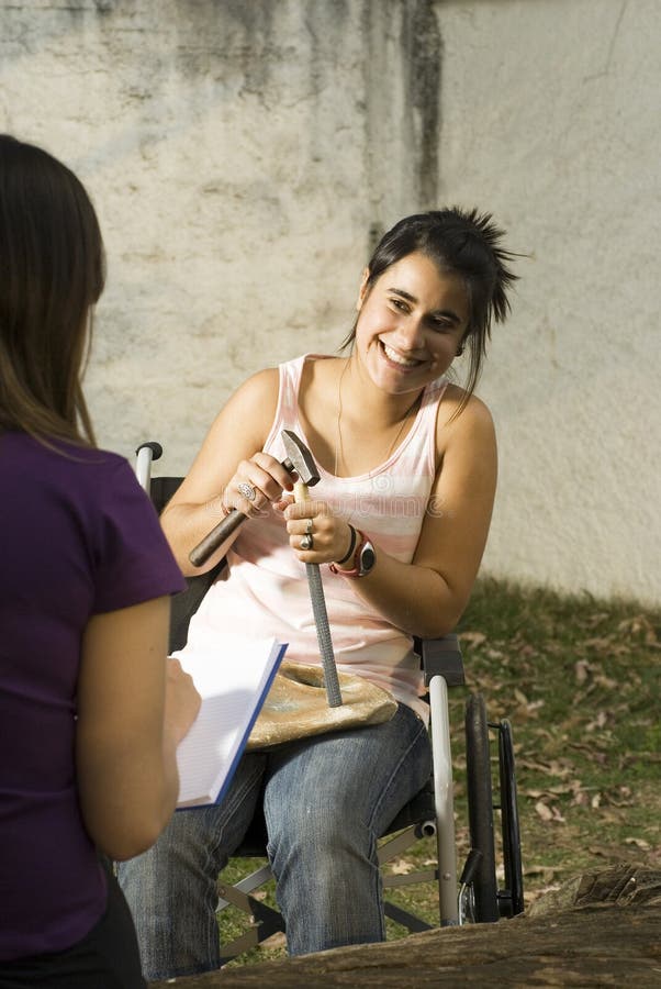 Girls smiling as she sits in wheelchair with hammer and chisel. Vertically framed photo. Girls smiling as she sits in wheelchair with hammer and chisel. Vertically framed photo.