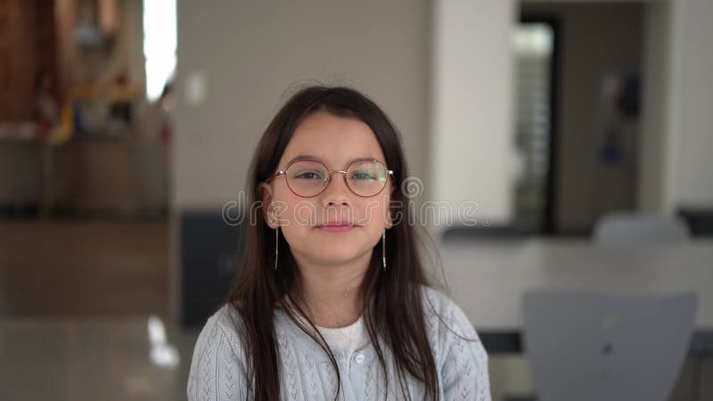 Muchacha con gafas y suéter de pie en el fondo borroso de la escuela. Concepto de niños educacionales almacen de video