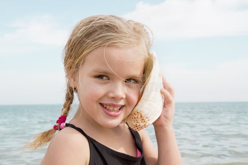Muchacha con la cáscara que escucha el mar fotos de archivo libres de regalías Muchacha con la cáscara que escucha el mar fotos de archivo libres de regalías