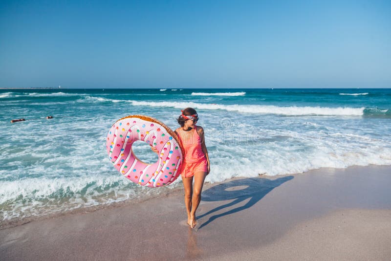 Muchacha con lilo del buñuelo en la playa imagen de archivo libre de regalías Muchacha con lilo del buñuelo en la playa imagen de archivo libre de regalías