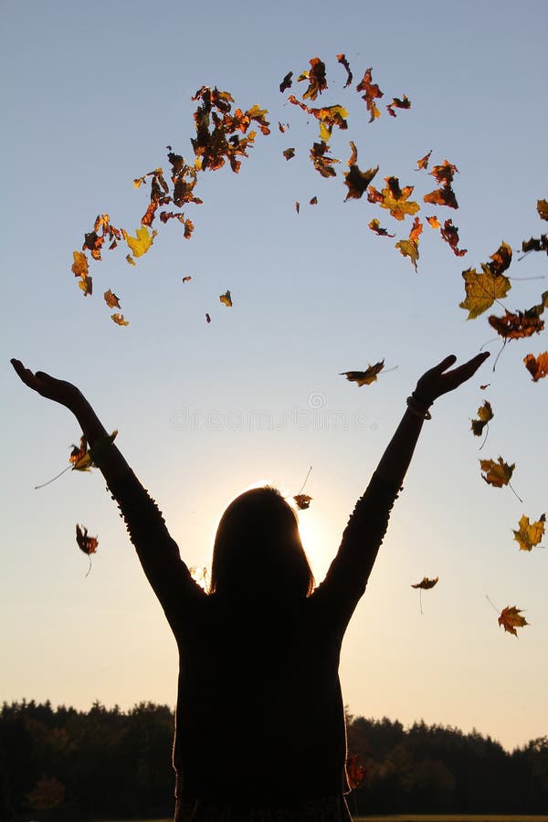 Silhouette of girl with outstretched arms, throwing autumn leaves in the sky. Silhouette of girl with outstretched arms, throwing autumn leaves in the sky