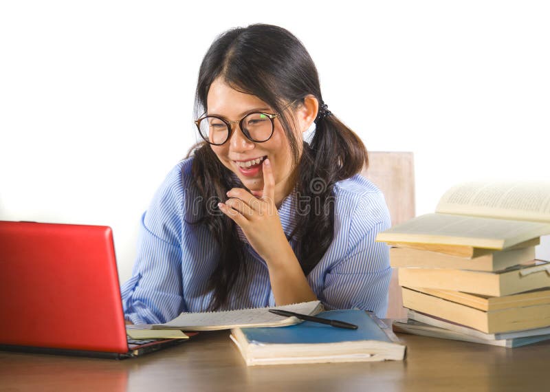 Muchacha coreana asiática dulce y feliz joven del estudiante en el funcionamiento de vidrios del empollón alegre en el ordenador fotos de archivo Muchacha coreana asiática dulce y feliz joven del estudiante en el funcionamiento de vidrios del empollón alegre en el ordenador fotos de archivo