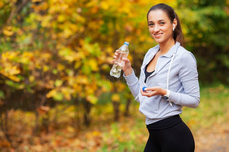 Muchacha de la aptitud Mujer hermosa joven en agua potable de la ropa de deportes en parque fotos de archivo libres de regalías Muchacha de la aptitud Mujer hermosa joven en agua potable de la ropa de deportes en parque fotos de archivo libres de regalías