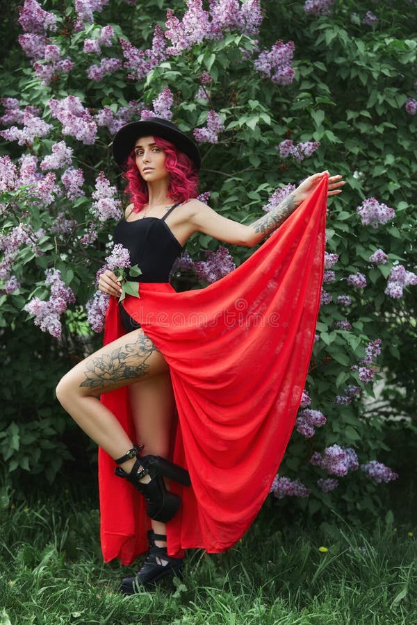 Muchacha de la moda con el pelo rojo y el sombrero grande, retrato de la primavera en colores de la lila en verano Vestido rosado foto de archivo Muchacha de la moda con el pelo rojo y el sombrero grande, retrato de la primavera en colores de la lila en verano Vestido rosado foto de archivo