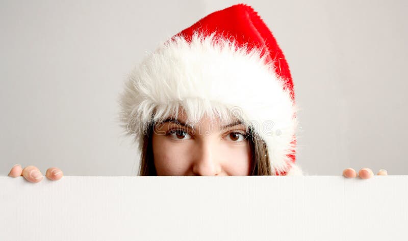 Muchacha de la Navidad que oculta detrás de una tarjeta en blanco