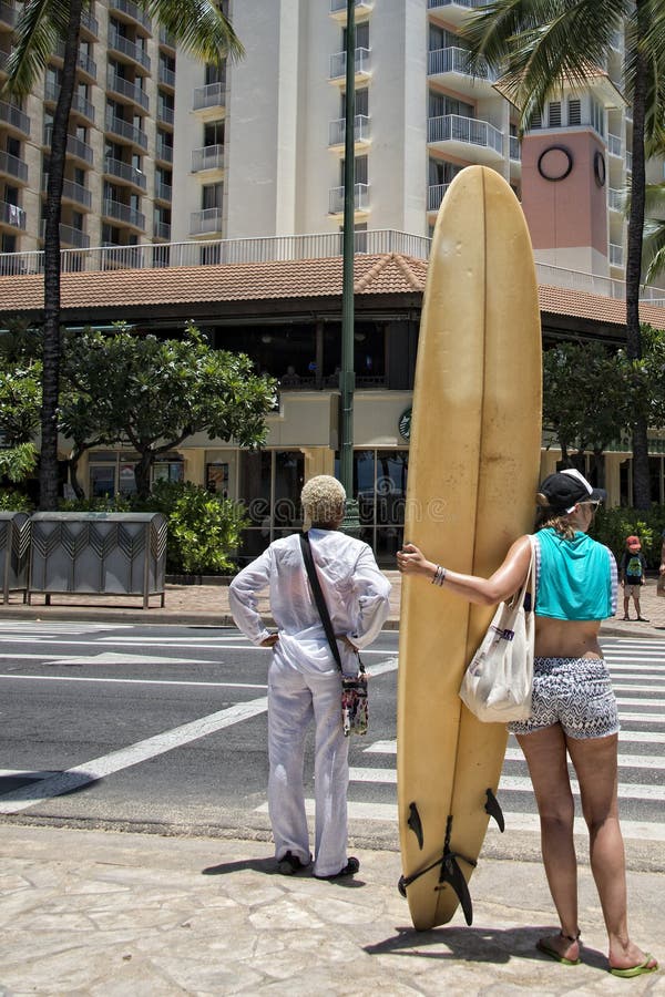 Muchacha de la persona que practica surf que cruza la calle en Waikiki fotografía de archivo libre de regalías Muchacha de la persona que practica surf que cruza la calle en Waikiki fotografía de archivo libre de regalías