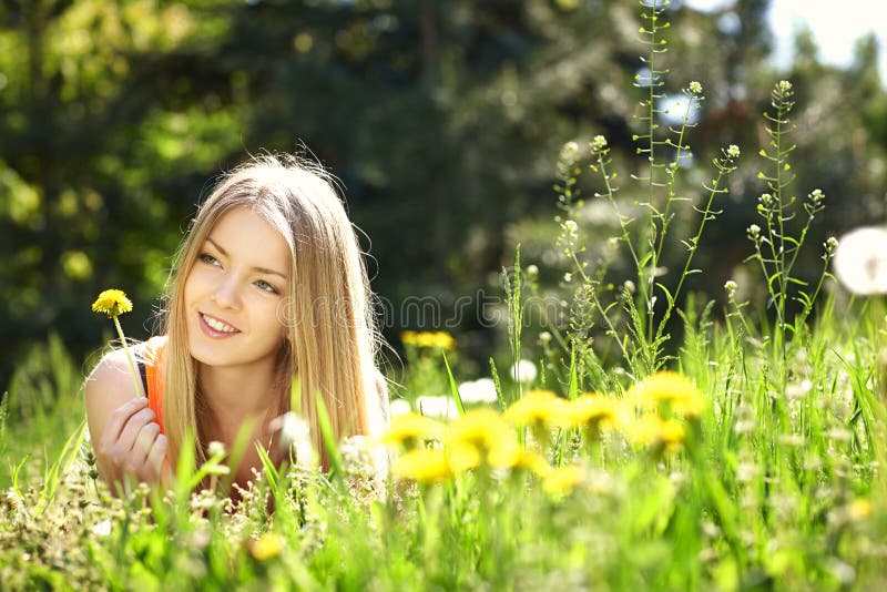 Muchacha de la primavera que miente en el campo de dientes de león imagenes de archivo Muchacha de la primavera que miente en el campo de dientes de león imagenes de archivo