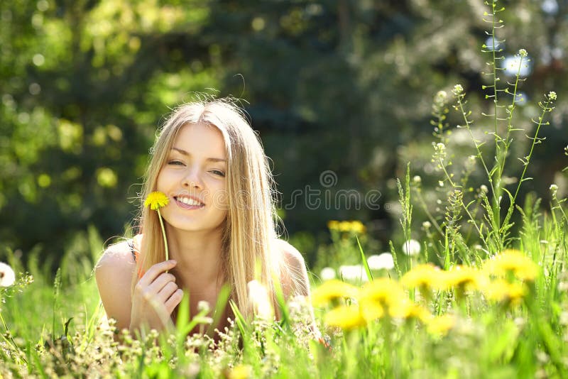 Muchacha de la primavera que miente en el campo de dientes de león fotos de archivo Muchacha de la primavera que miente en el campo de dientes de león fotos de archivo