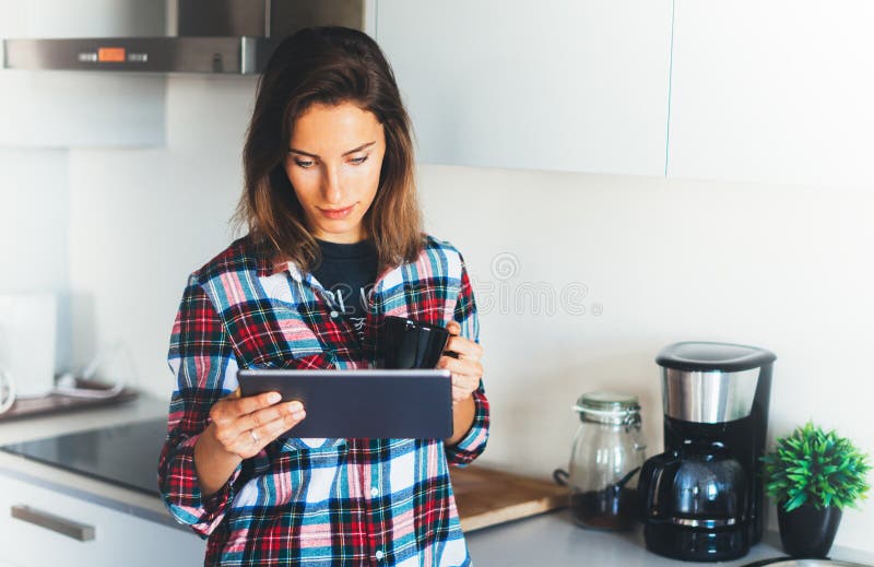 Muchacha del inconformista que usa el café de la tecnología y de la bebida de la tableta en la cocina, persona de la muchacha que imágenes de archivo libres de regalías Muchacha del inconformista que usa el café de la tecnología y de la bebida de la tableta en la cocina, persona de la muchacha que imágenes de archivo libres de regalías