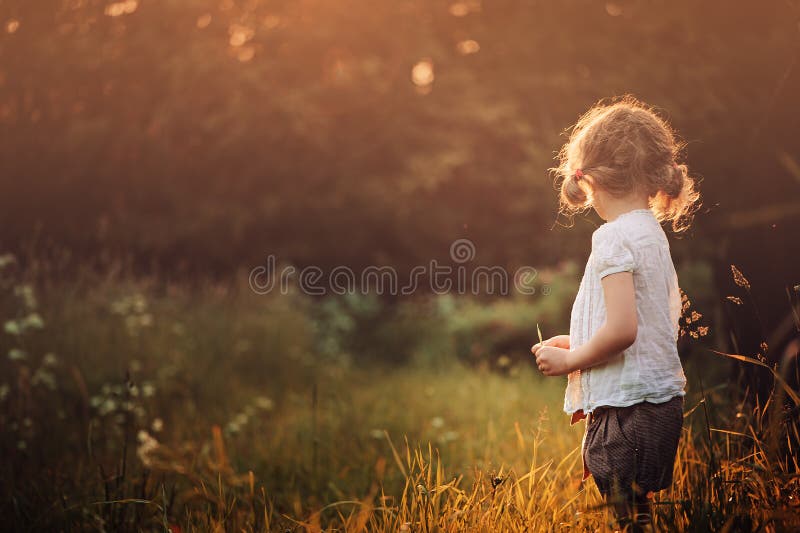 Muchacha del niño en la camisa blanca en el paseo en campo de la puesta del sol del verano imagenes de archivo Muchacha del niño en la camisa blanca en el paseo en campo de la puesta del sol del verano imagenes de archivo