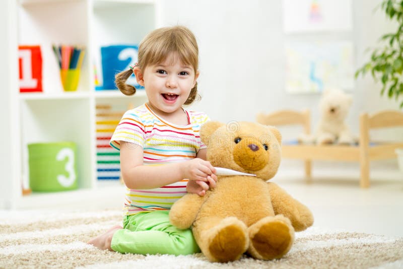 Muchacha del niño que juega al doctor con el juguete de la felpa en casa fotografía de archivo Muchacha del niño que juega al doctor con el juguete de la felpa en casa fotografía de archivo