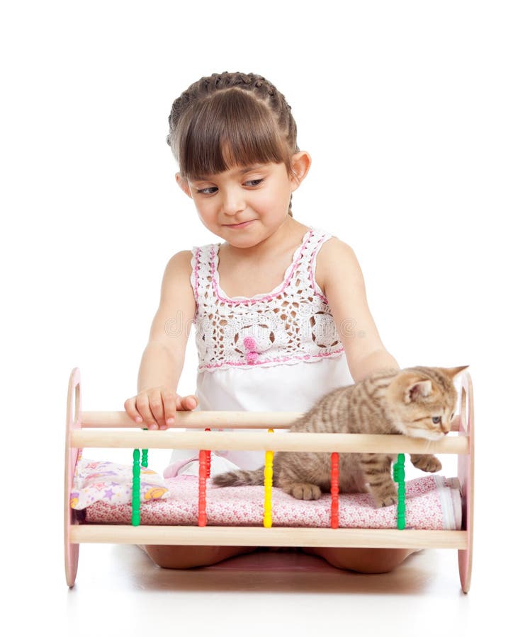 Child girl plays with cat kitten and rocking him in doll crib isolated. Child girl plays with cat kitten and rocking him in doll crib isolated